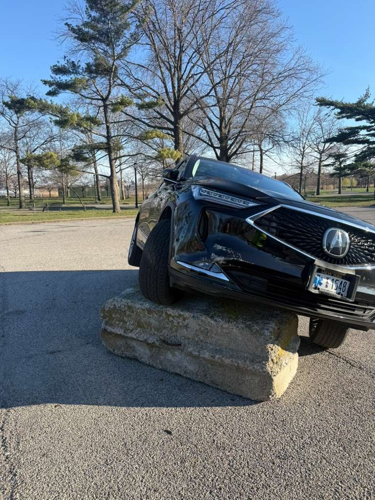 Before: Acura MDX stuck on a curb barrier Black Acura MDX lifted off a concrete curb barrier in a Queens park lot — JG Towing recovery.