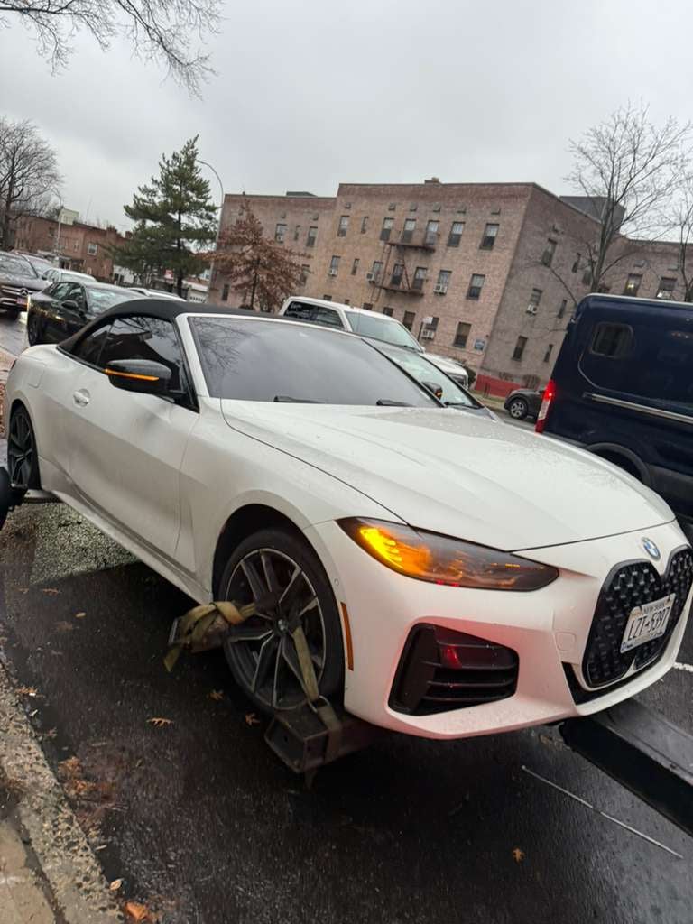 BMW 4-Series convertible on the flatbed White BMW 4-Series convertible strapped to JG Towing flatbed in Queens on a gray afternoon.