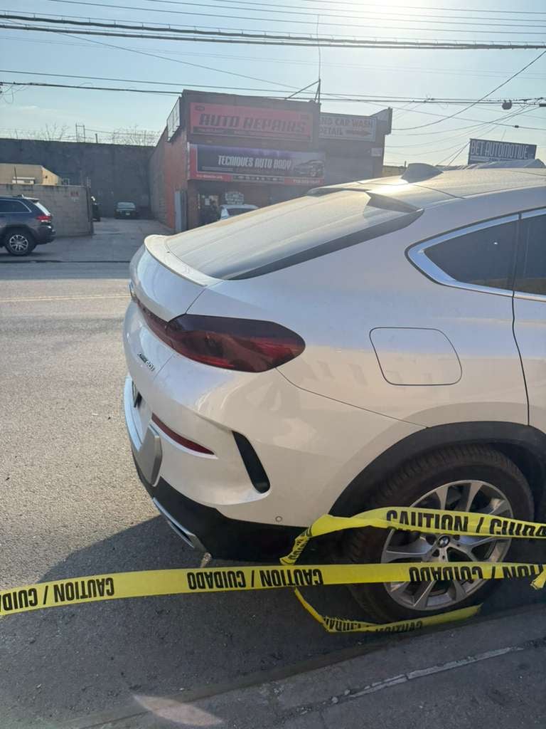 BMW X6 scene in Queens — caution tape up, clearance in progress White BMW X6 cordoned off with caution tape after an incident on a Queens avenue — JG Towing.