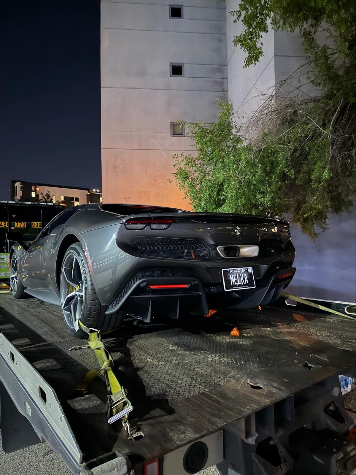 Overnight Ferrari flatbed recovery in Queens, NY Ferrari 296 GTB secured on JG Towing flatbed at night in front of an apartment tower.