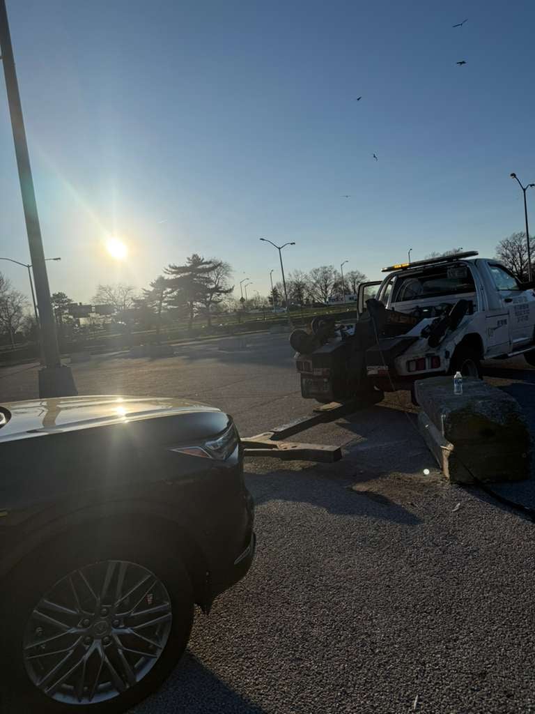 Same Acura MDX — long-distance haul from Flushing Meadows-Corona Park, Queens Same Acura MDX from the accident recovery loaded on JG Towing wrecker for the long-distance haul out of Flushing Meadows-Corona Park, Queens, at sunset.