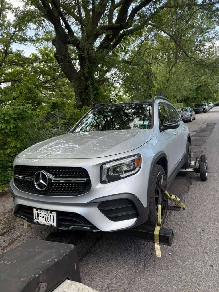 Mercedes-Benz GLB wheel-lift in Queens, NY Silver Mercedes-Benz GLB on JG Towing wheel-lift under shade trees.